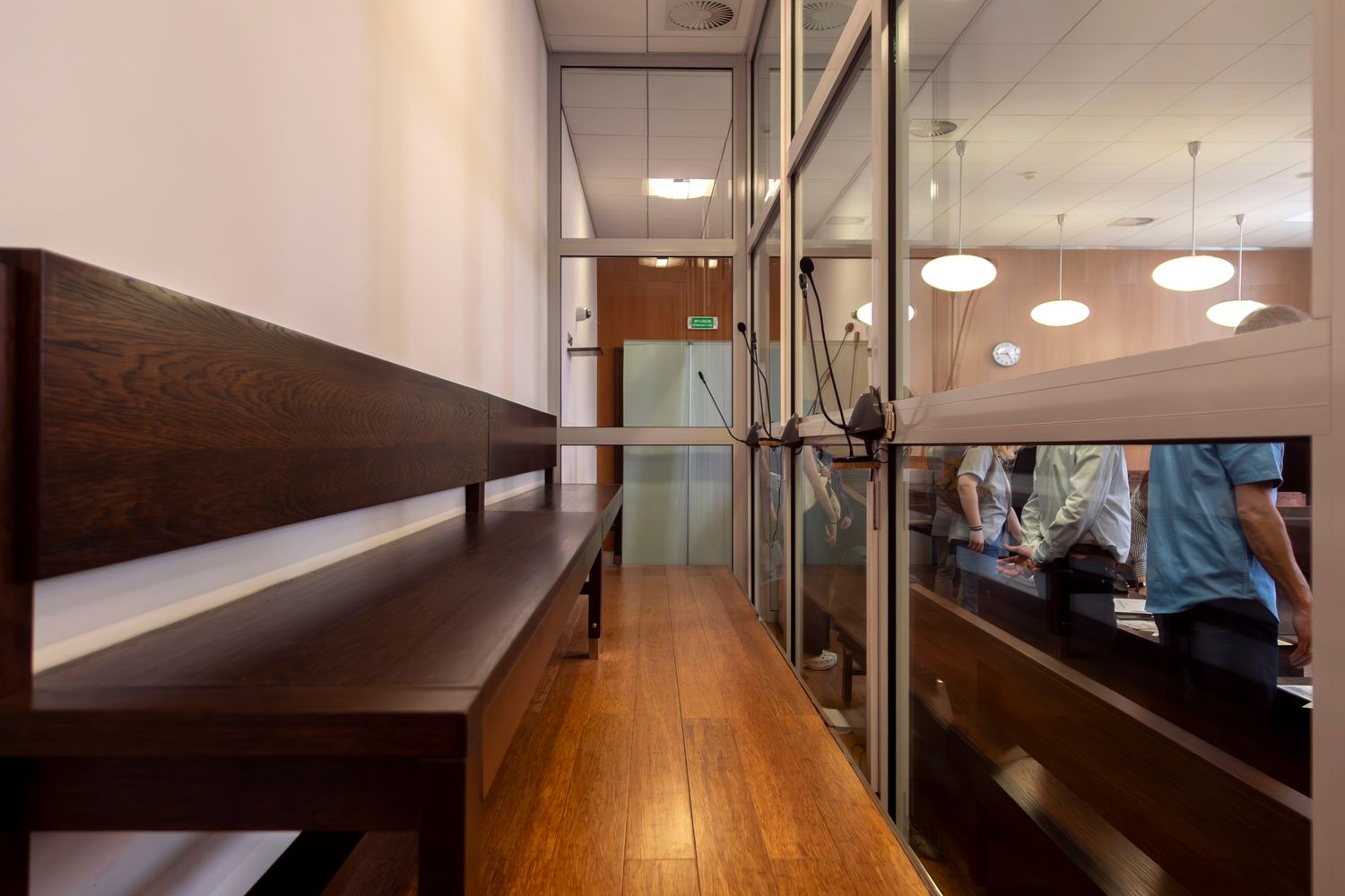 An empty courtroom with rows of wooden gallery benches and a judge's bench