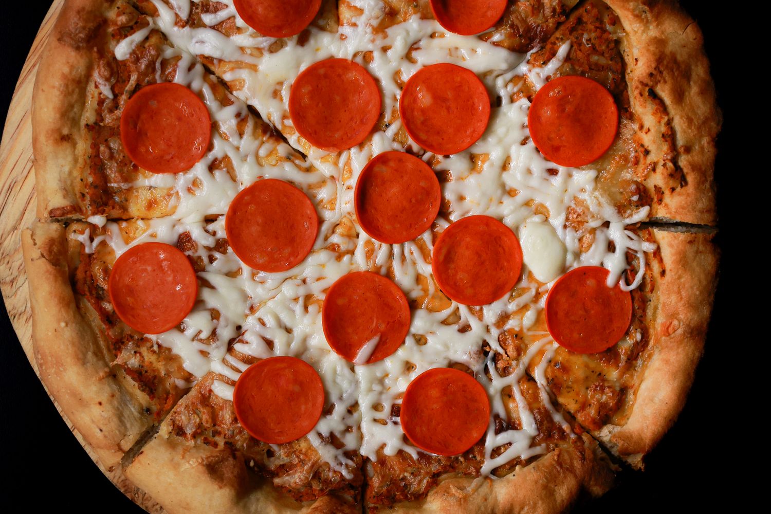 A pepperoni pizza fresh from the oven on a wooden serving board