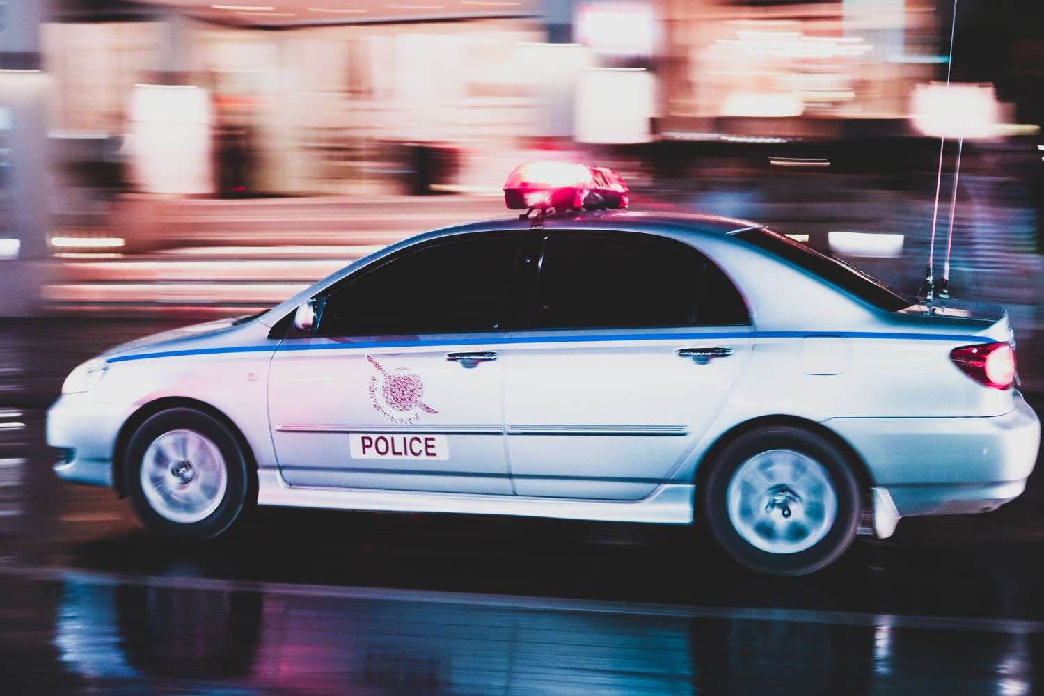 A police car with flashing lights on a dark roadway
