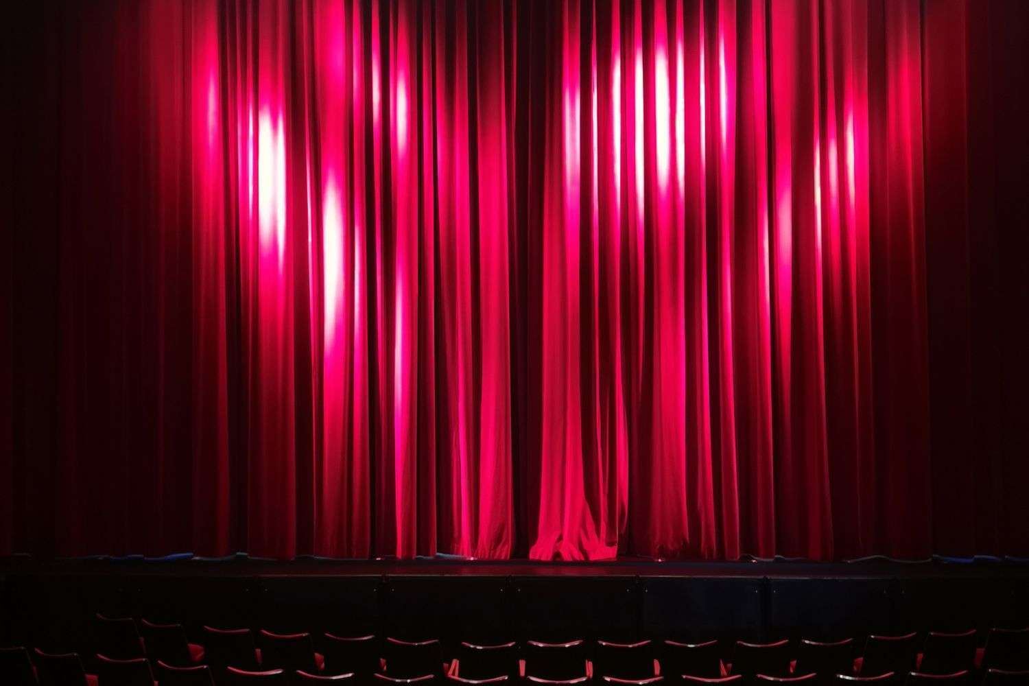 An empty theater stage with red curtains before a performance