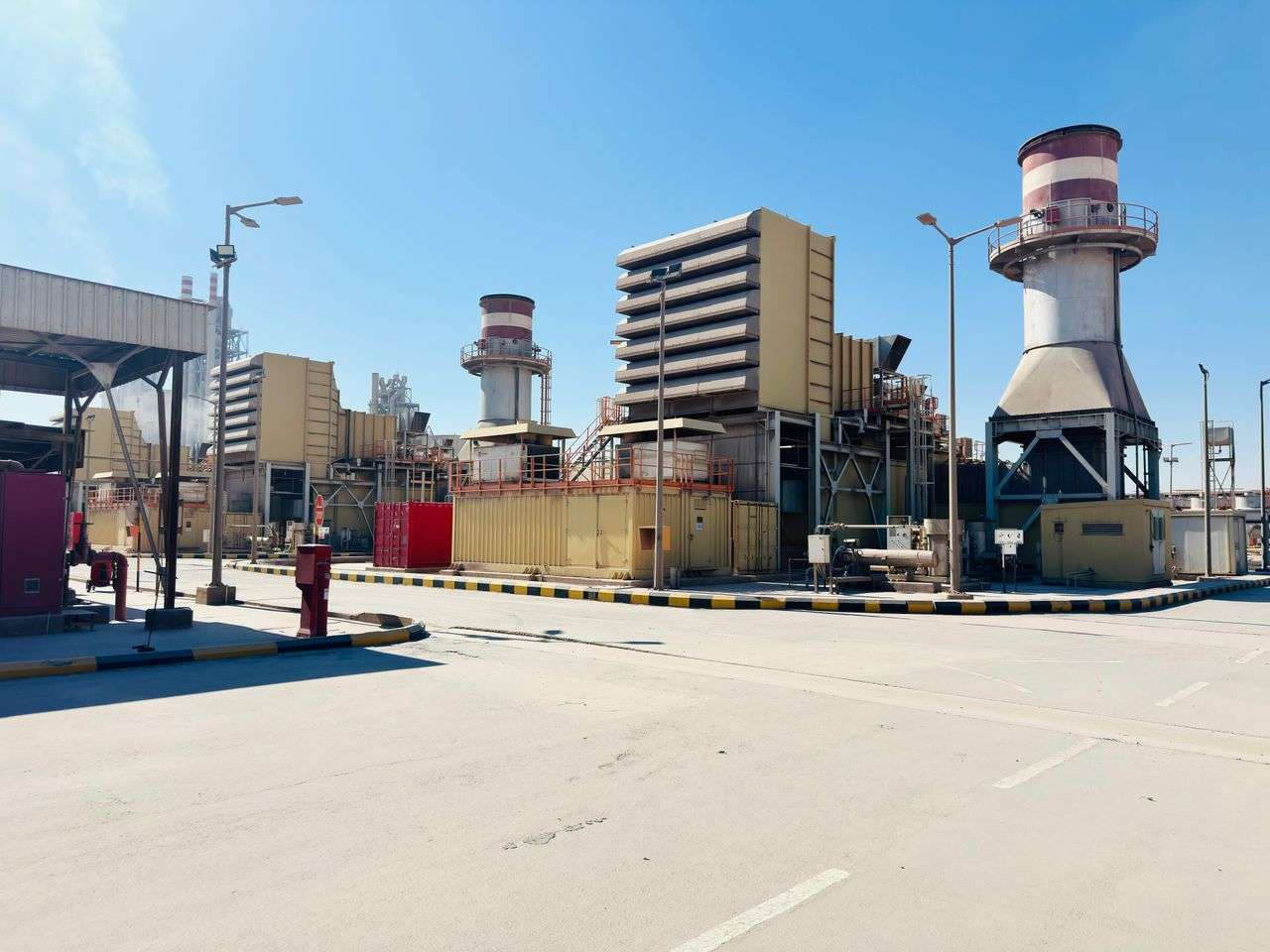 Industrial power plant with stacks and steam under a clear blue sky