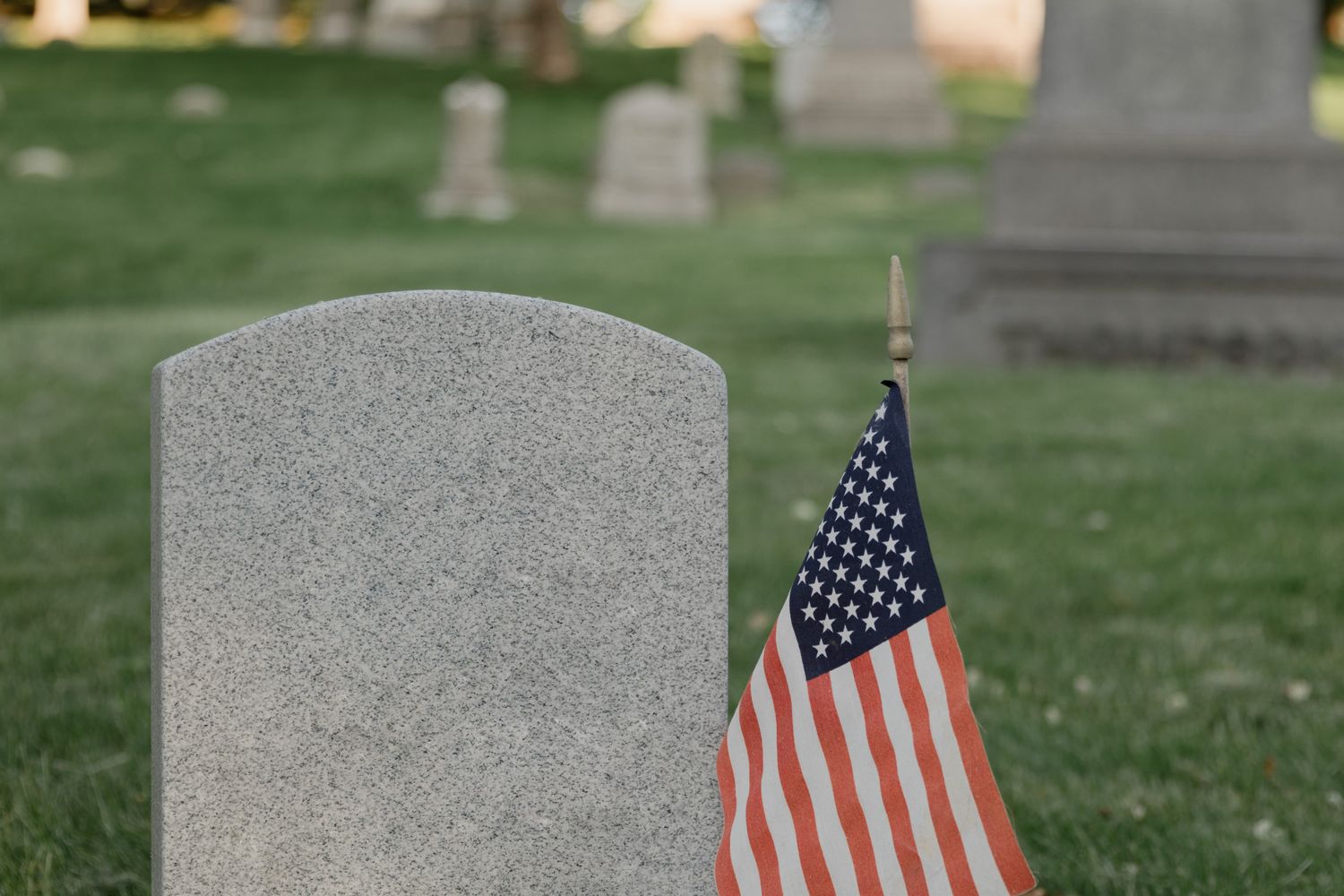 An American flag placed at a veteran's gravestone in a cemetery