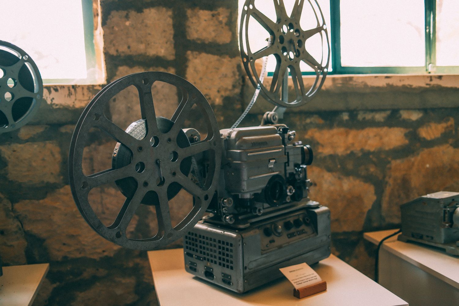 A vintage film projector sits beside reels of classic cinema film