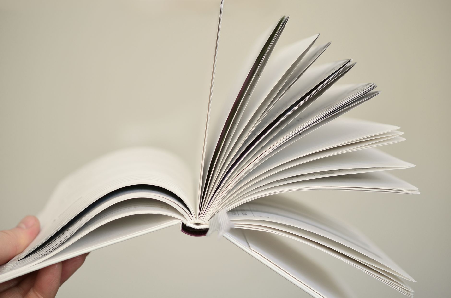 Close-up of an open book with a hand holding its pages fanned open