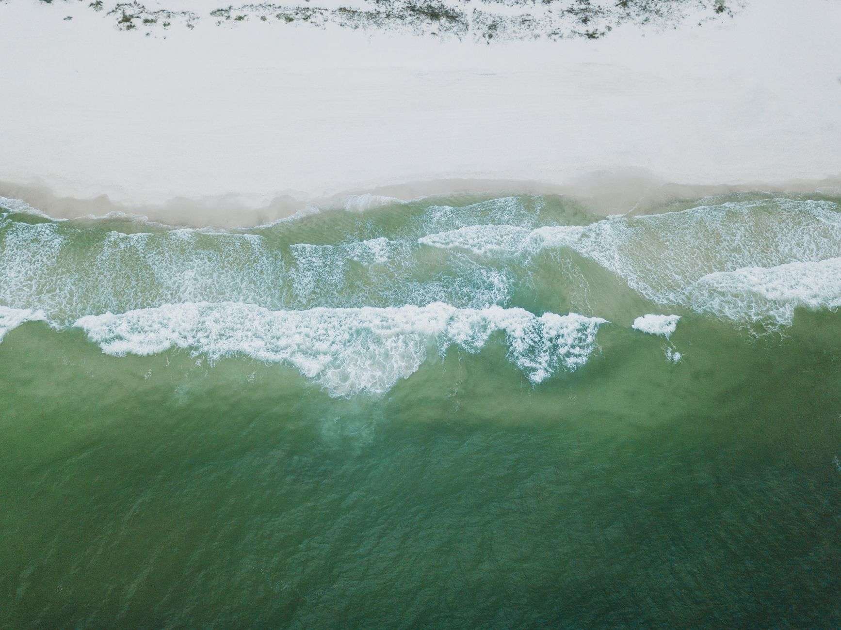 Aerial view of waves meeting a sandy beach along the Alabama Gulf Coast