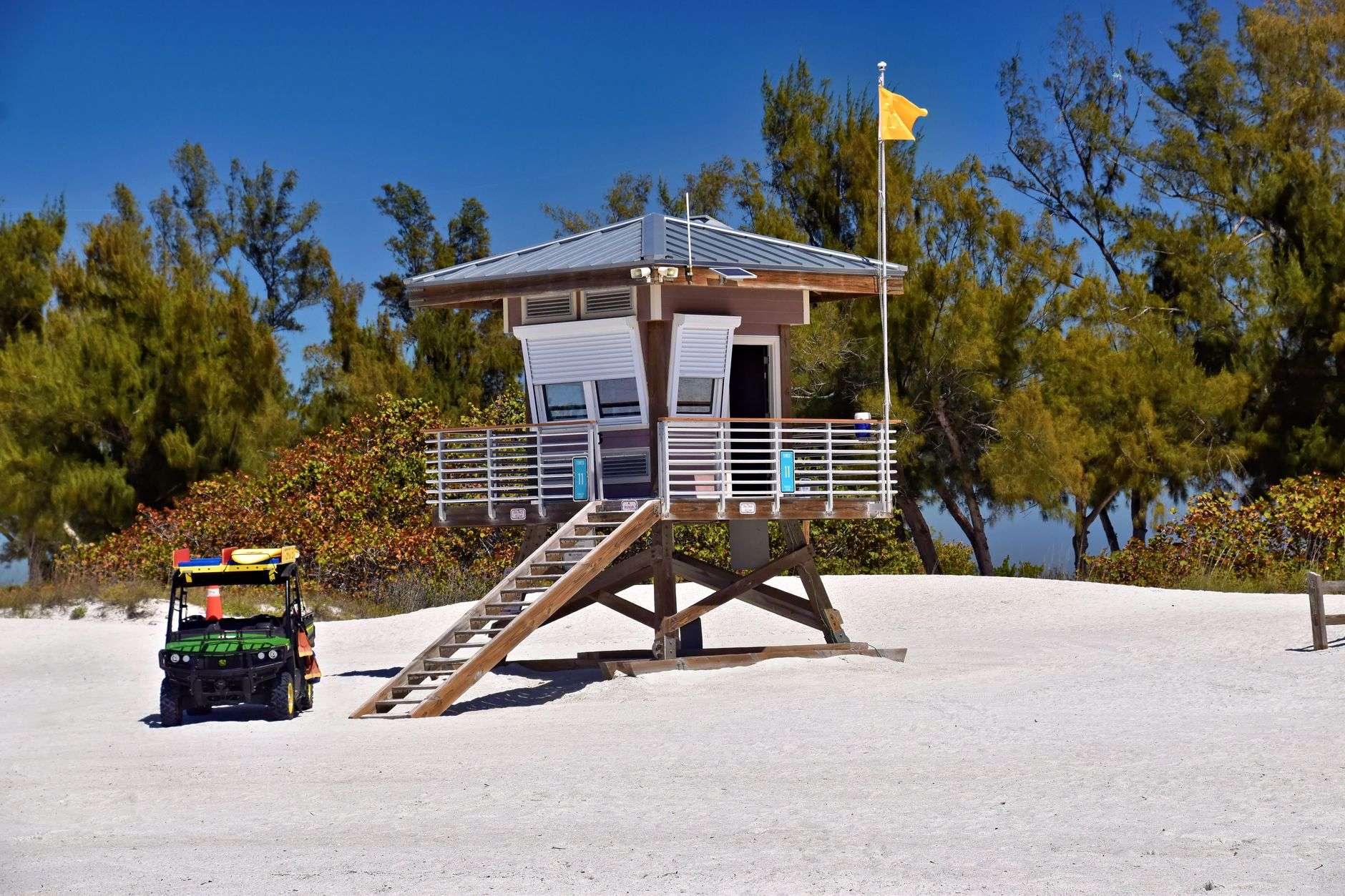 A lifeguard station on a sunny Gulf Coast beach with white sand and blue sky