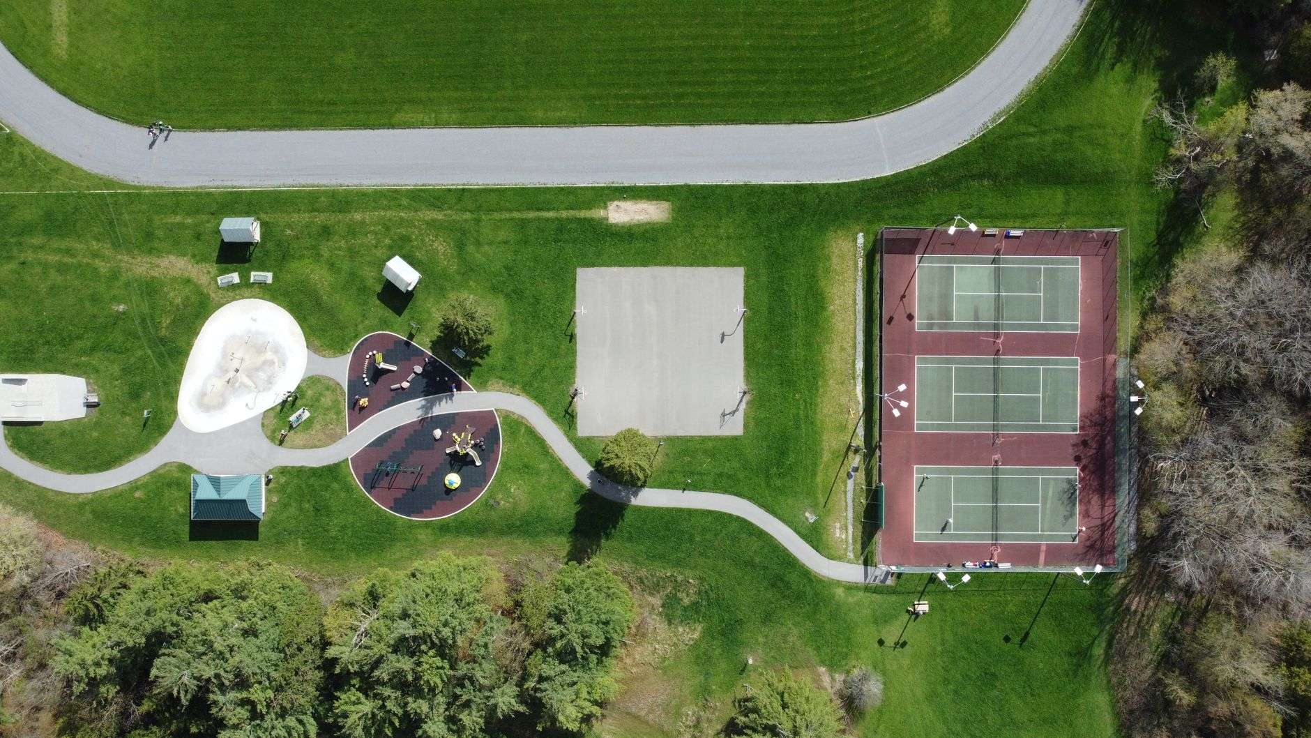 Aerial view of tennis courts, a playground and green space at a community recreation park