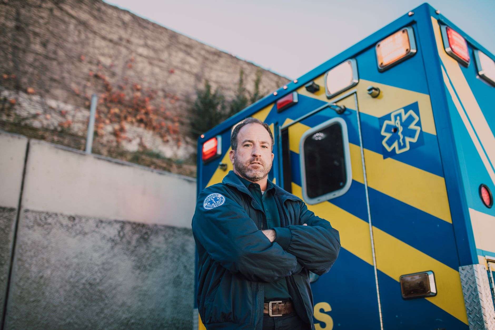 A paramedic in uniform standing behind an emergency ambulance