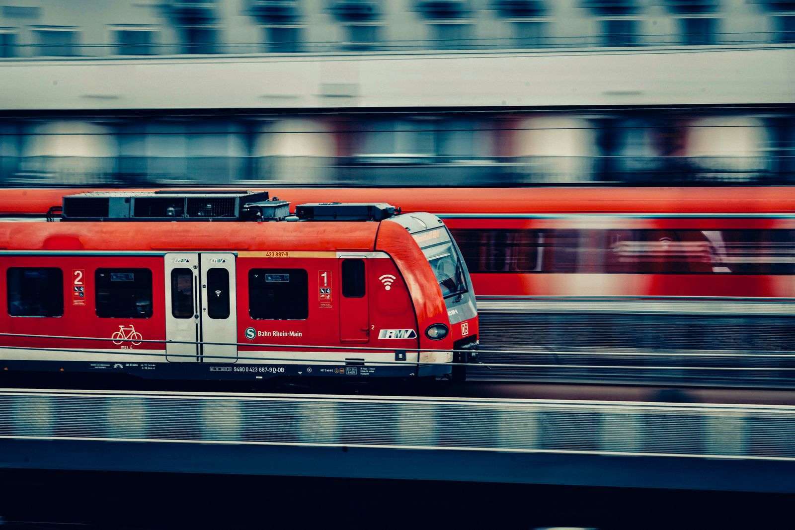 A red passenger train moving at speed through a landscape