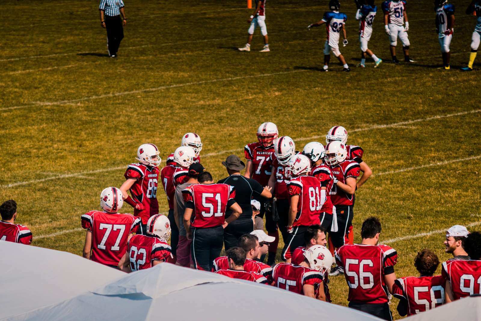 A football coach directs players from the sideline during a game