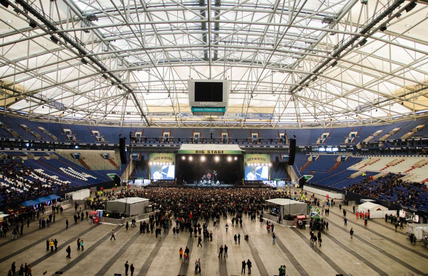 Interior view of a large indoor arena with tiered stadium seating surrounding a central floor area