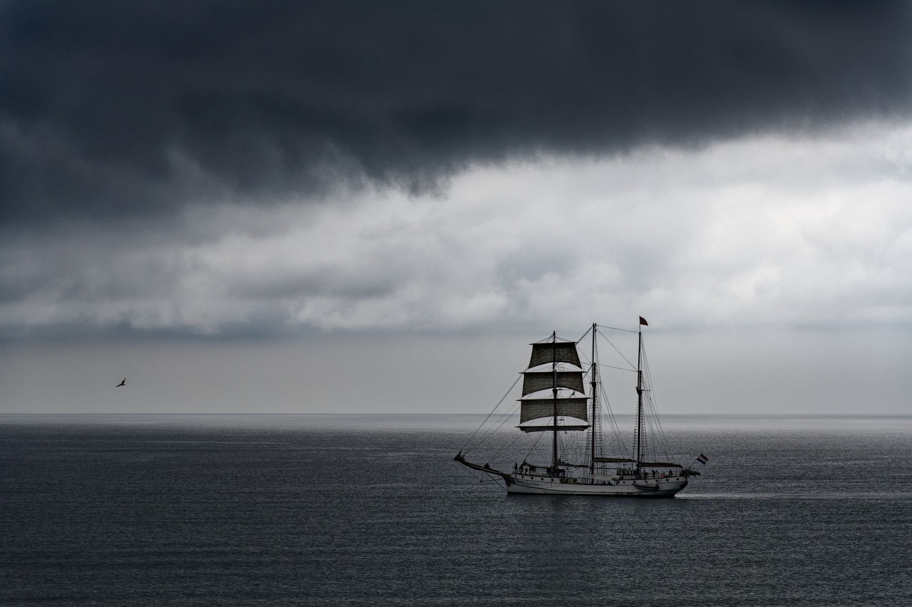 Dark storm clouds gathering over a sailing vessel on open water