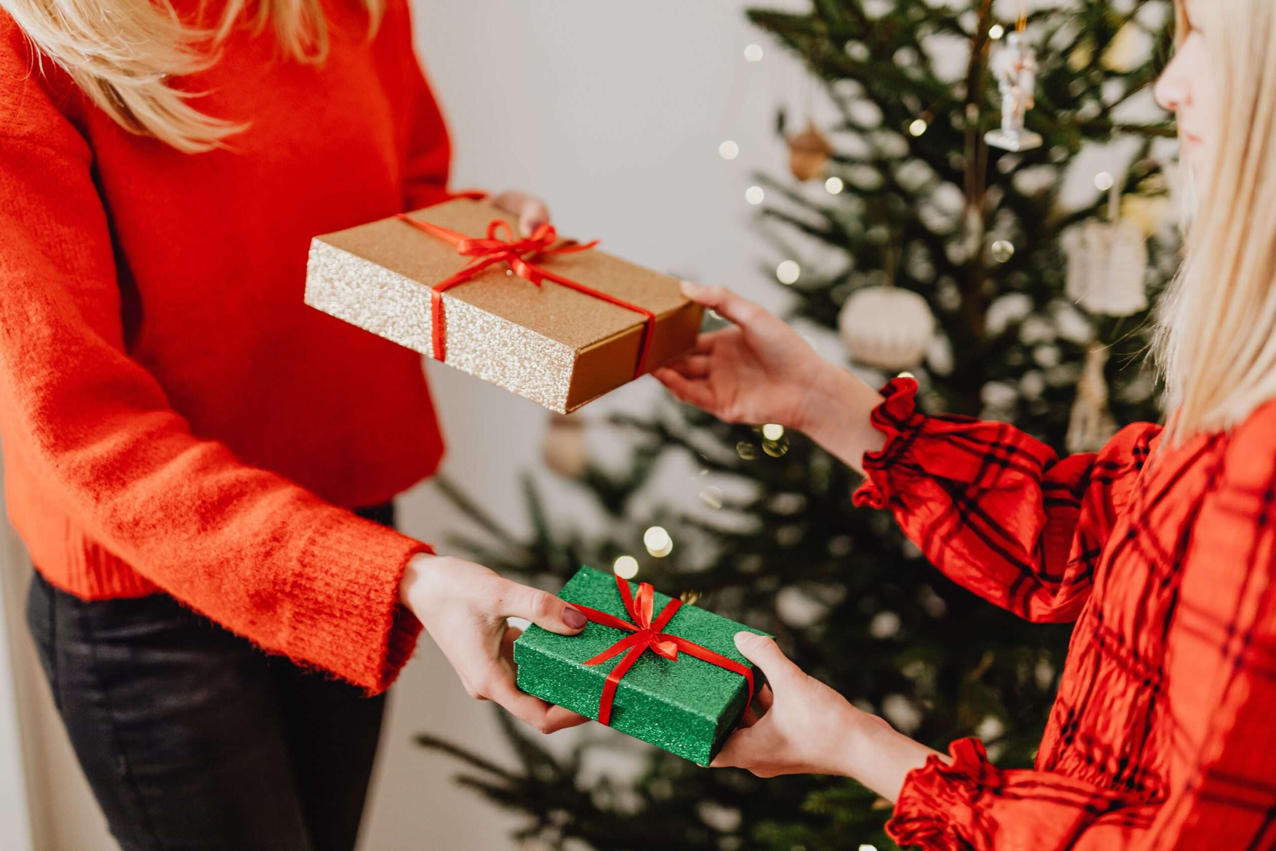 Wrapped Christmas gifts exchanged in front of a decorated tree during a holiday gift drive