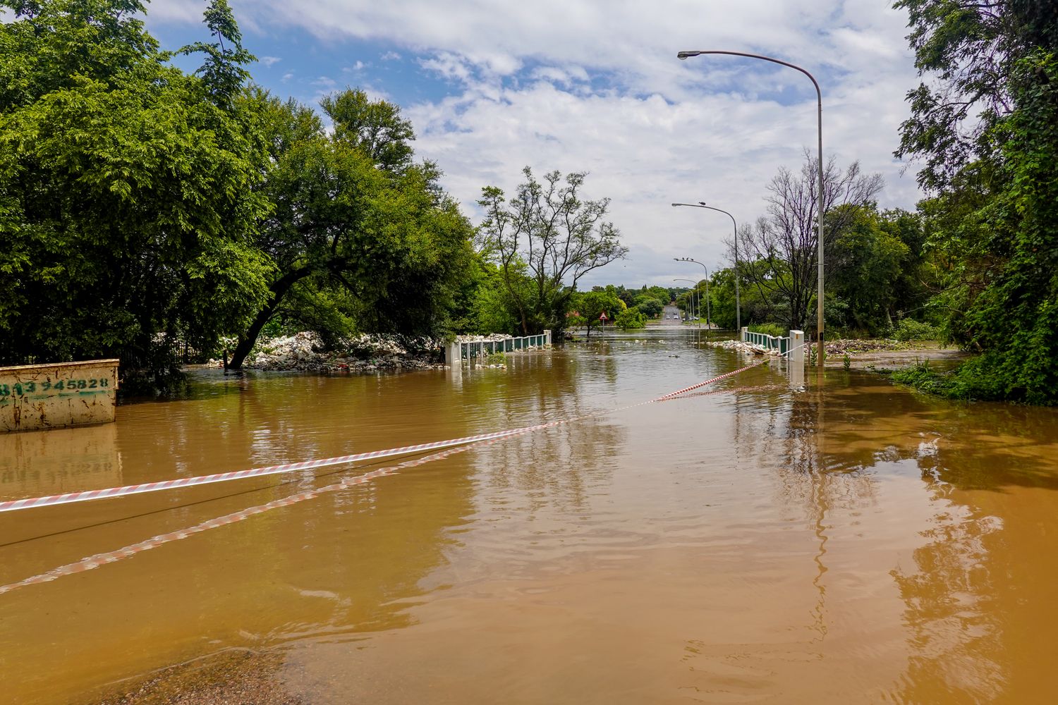 Flooded creek carrying debris beneath a small rural bridge