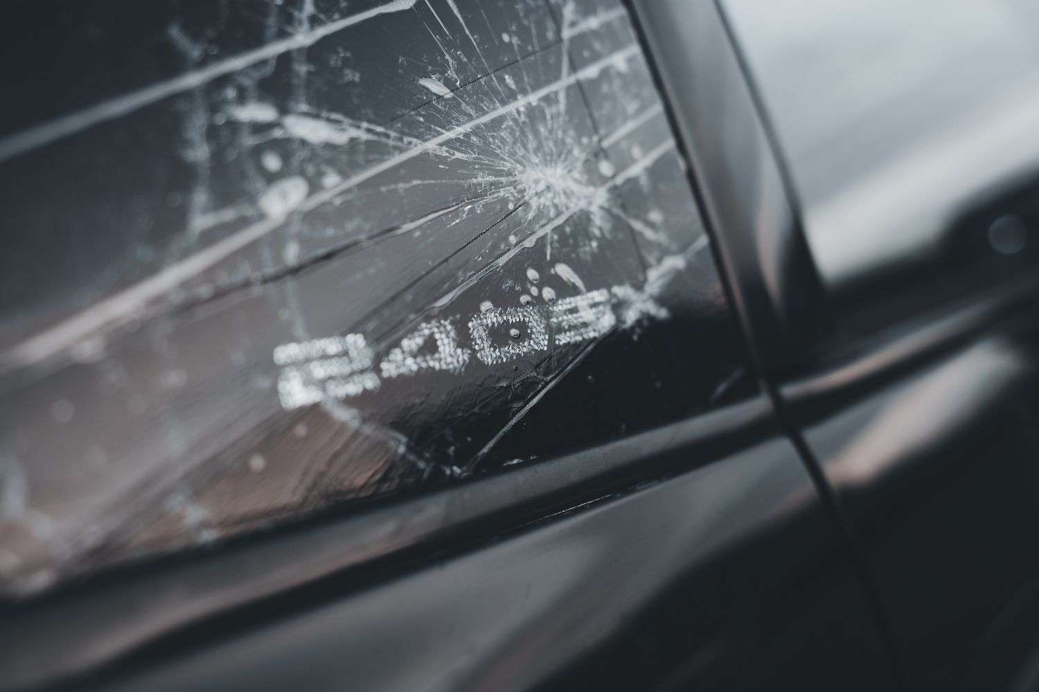 A car with a shattered rear window parked along a road
