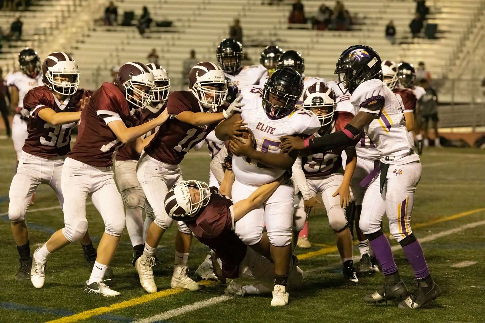 A high school football player carries the ball during a game