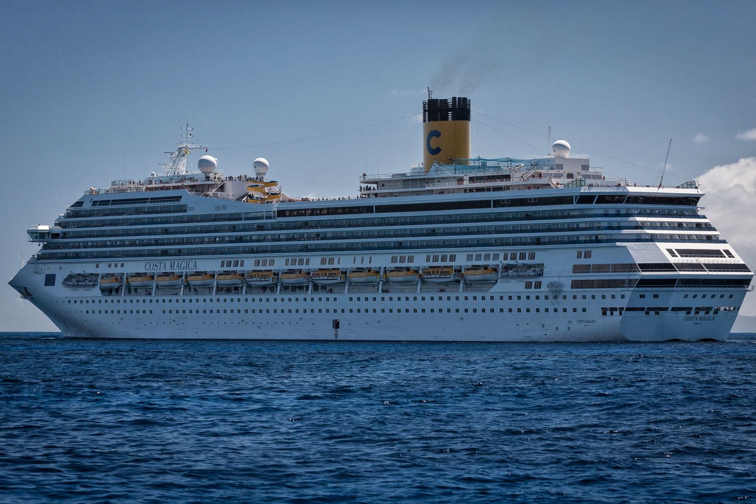 A cruise ship sailing on calm blue water near the coast