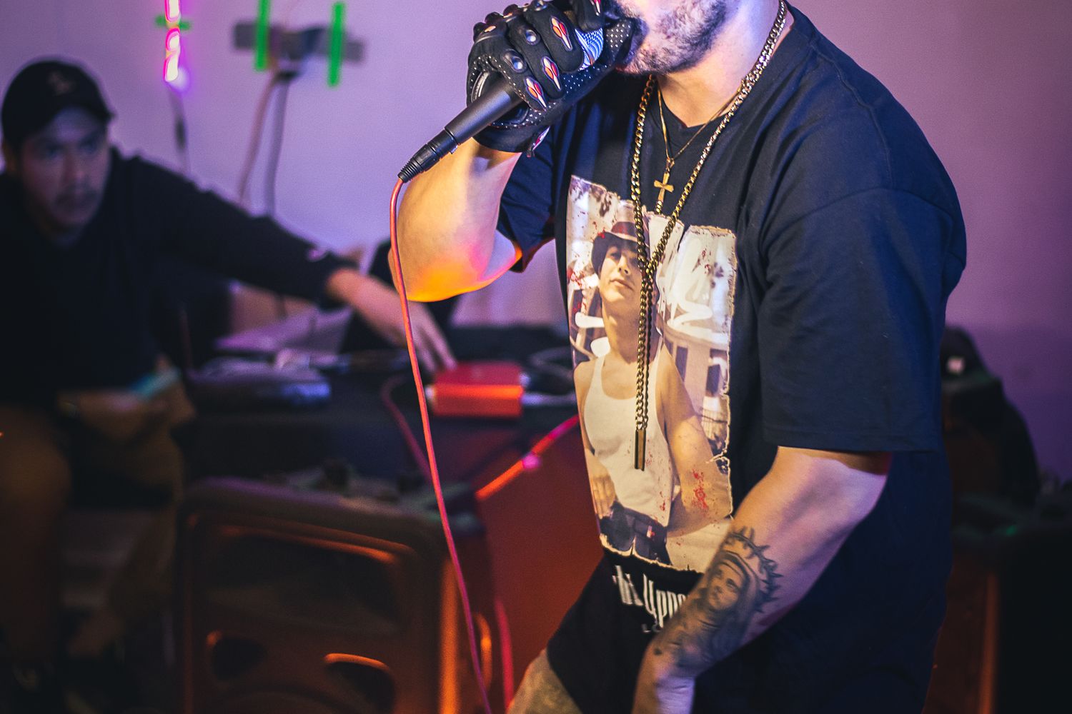 A hip hop performer raps into a microphone under neon stage lighting
