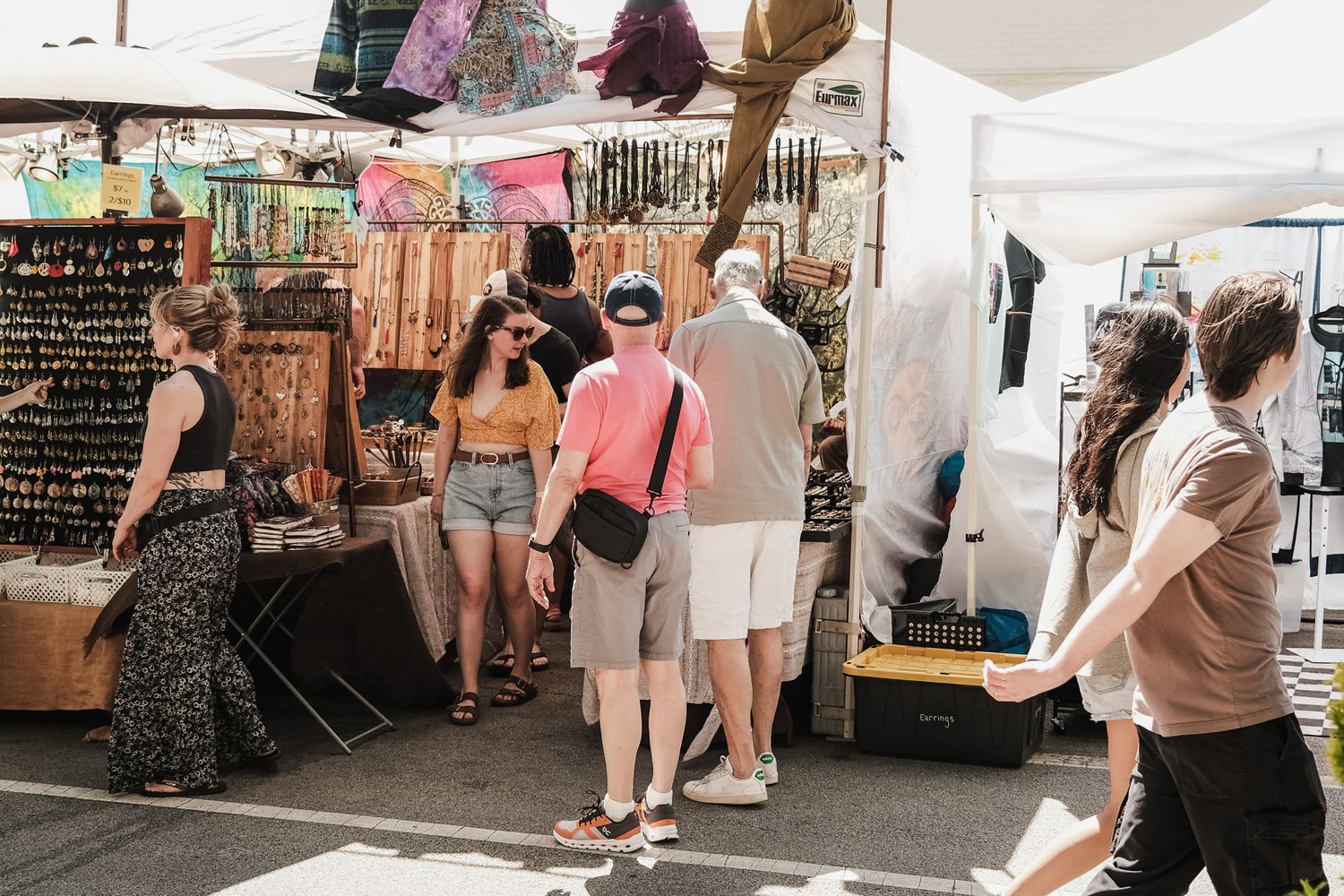 White tents line a boardwalk as visitors browse artist booths at an outdoor festival