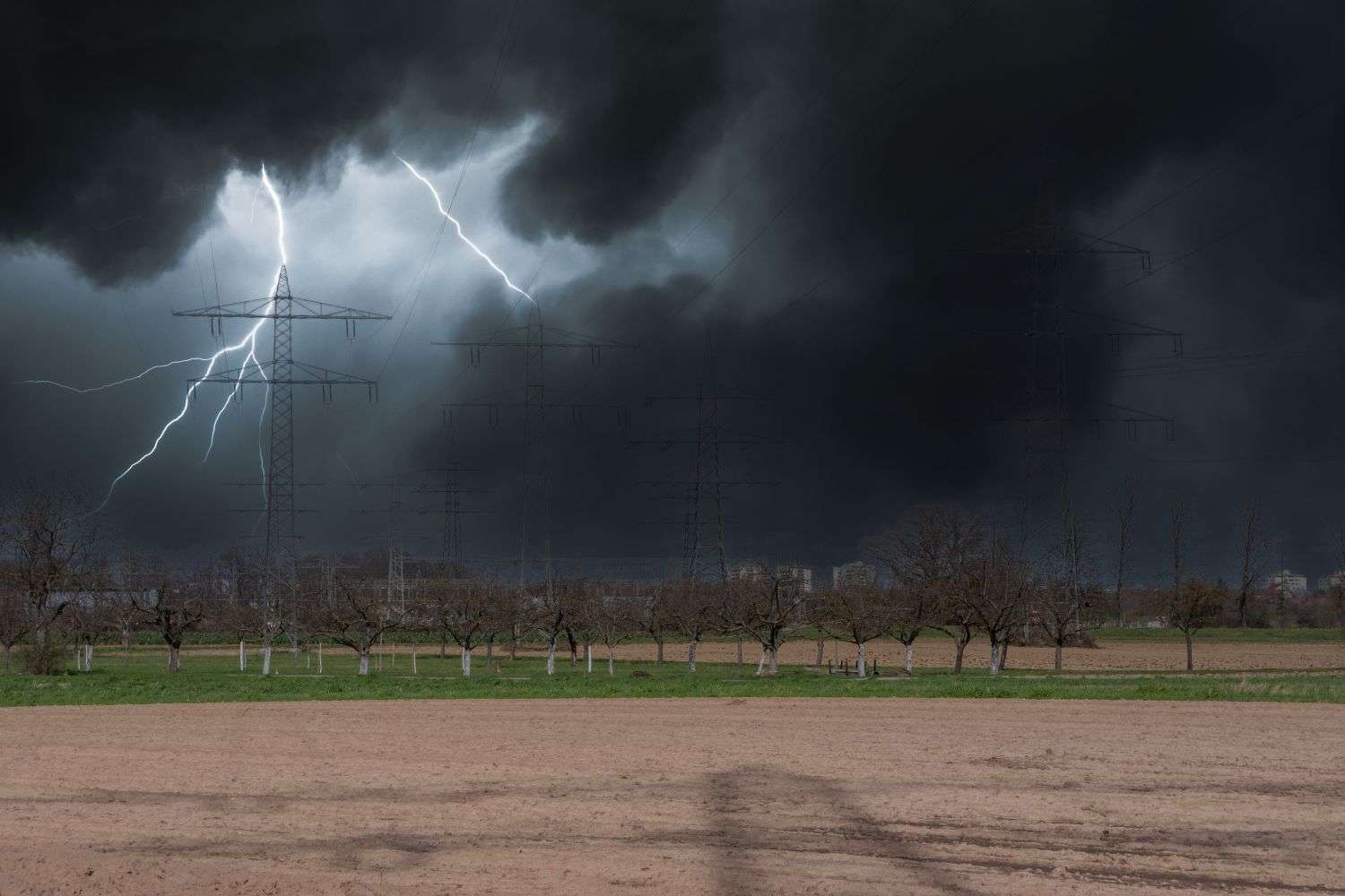 Severe thunderstorm clouds darken the sky above a city with power lines in view