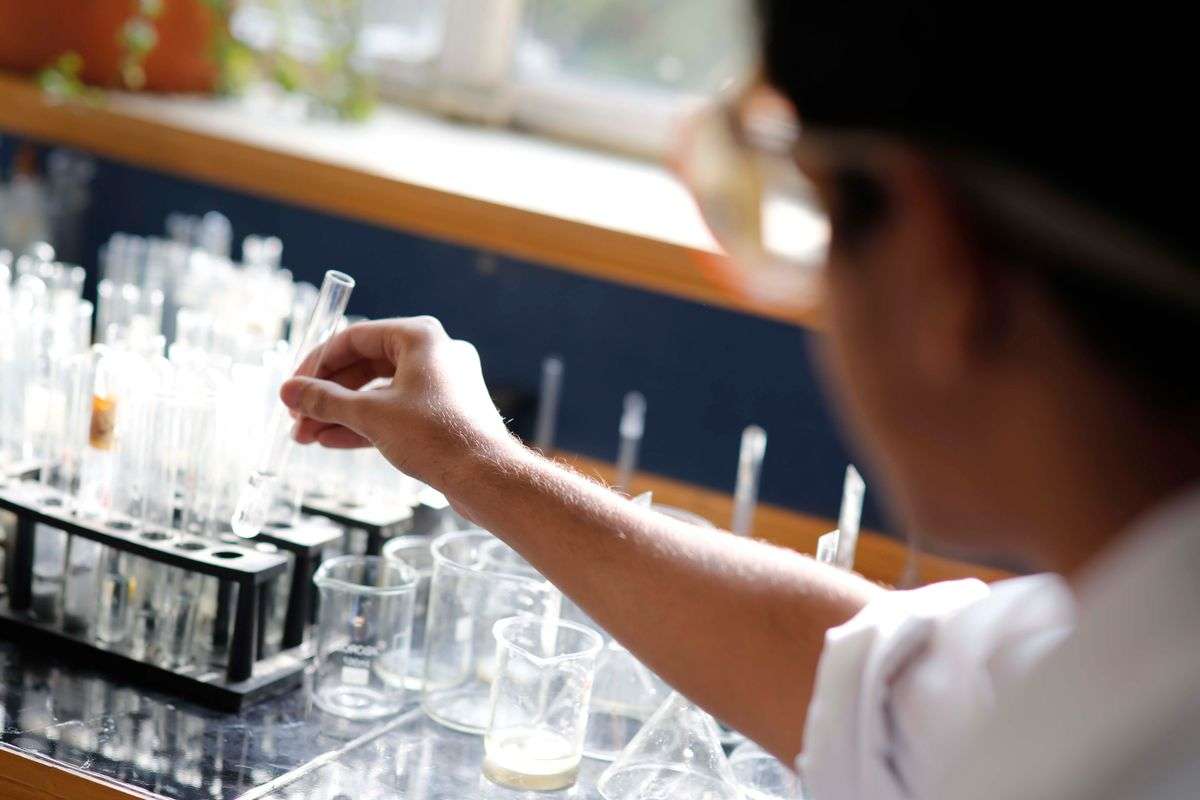 A student in safety gear conducting a chemistry experiment with test tubes in a laboratory