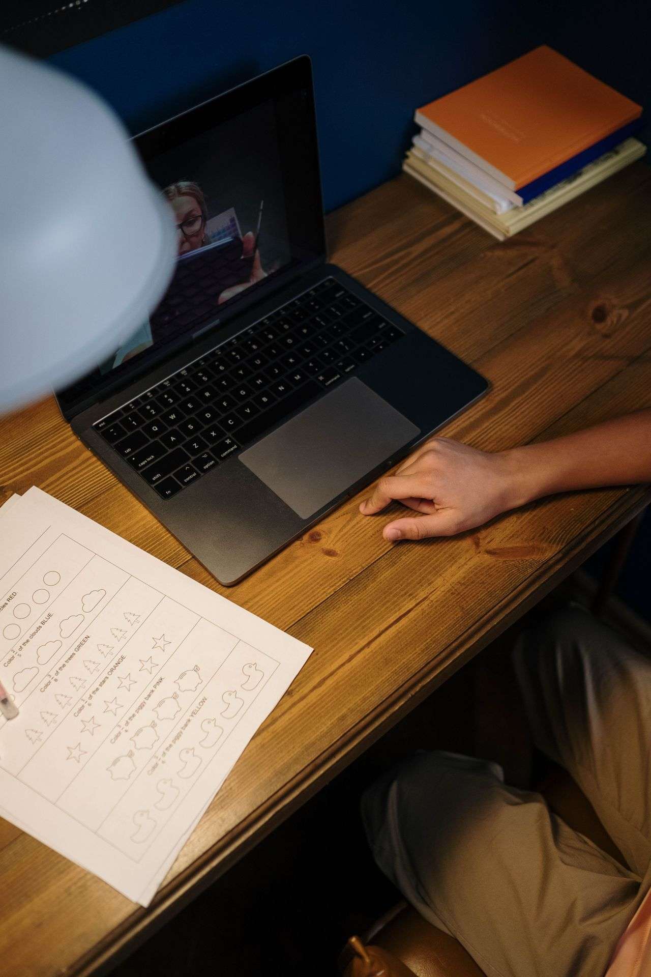 A student wearing earphones follows an online class on a laptop at home