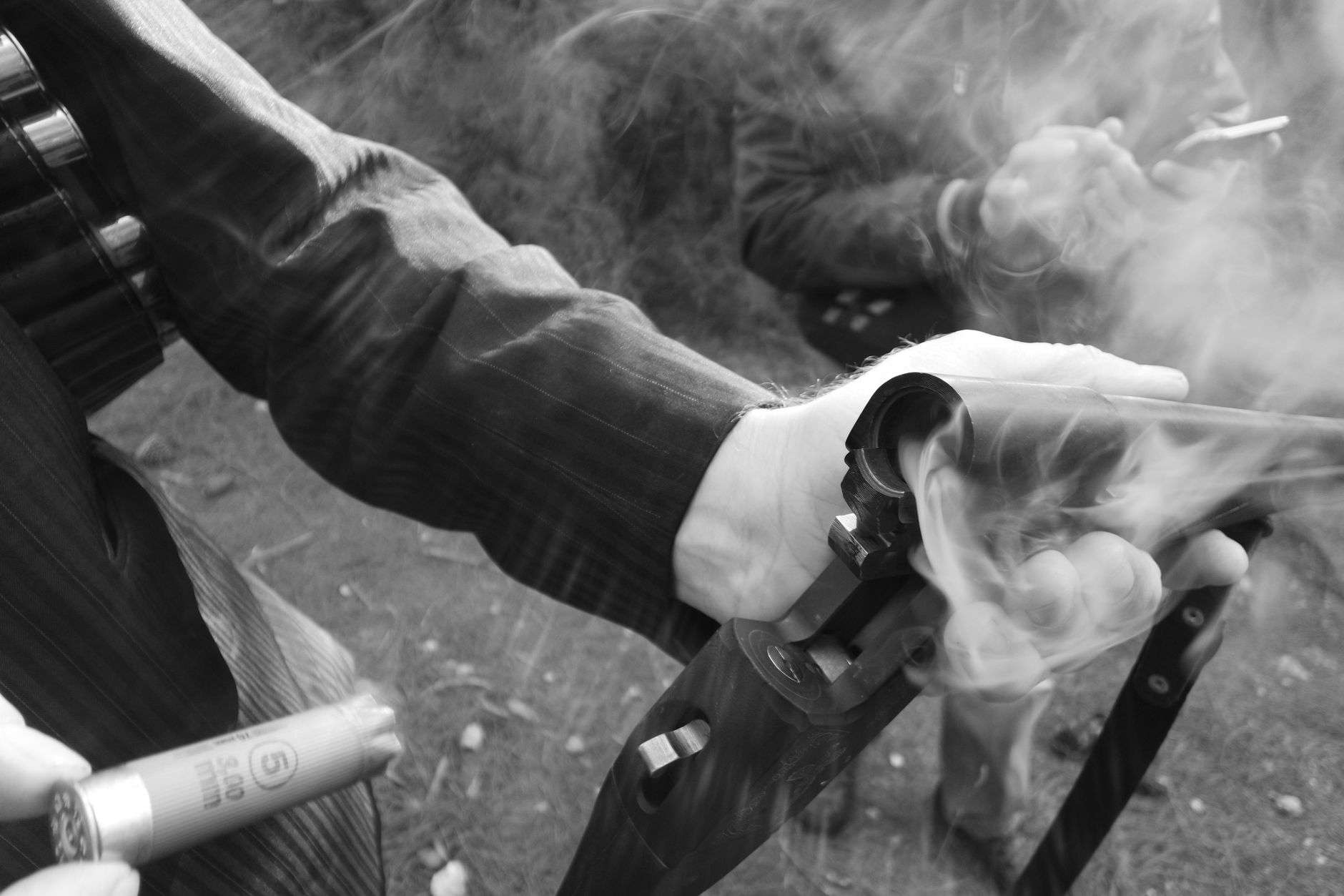 A shooter aiming a shotgun at clay targets on an outdoor range