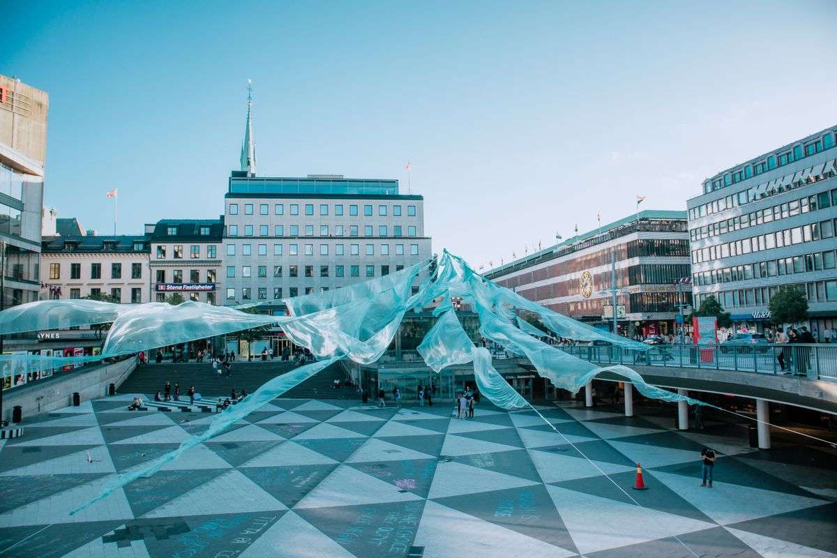 Modern art installation displayed in a city square surrounded by buildings