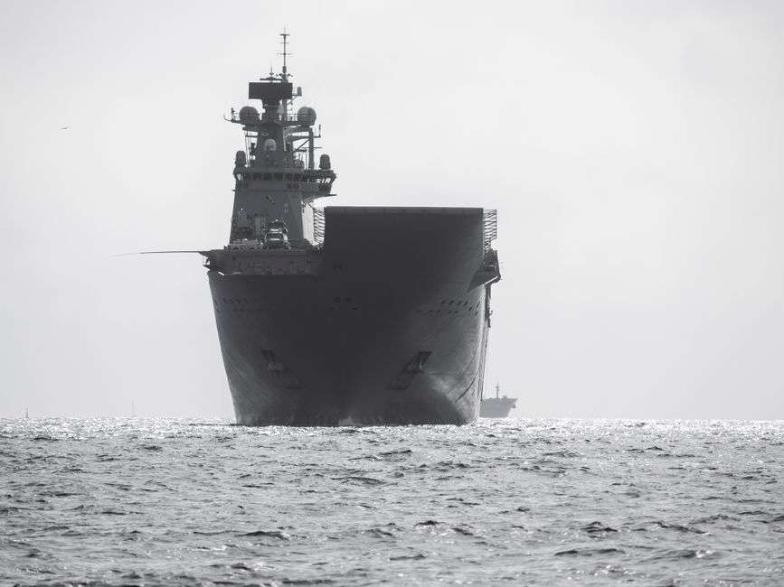 A large gray aircraft carrier underway on the water