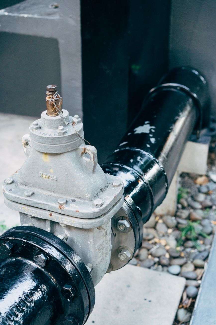 Close-up of a metal valve attached to a large industrial water pipe