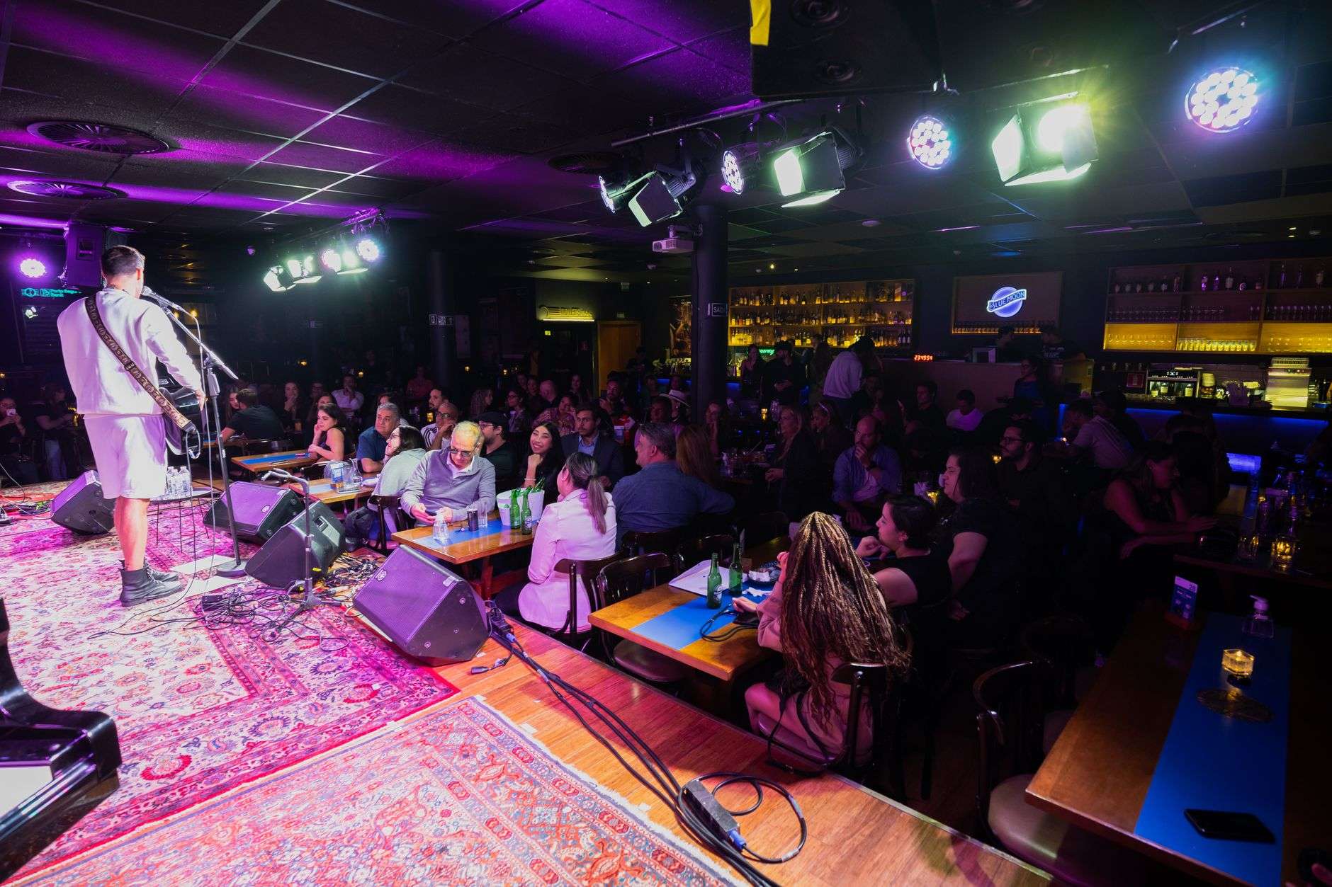 Musicians performing on stage at a crowded bar during a community benefit event