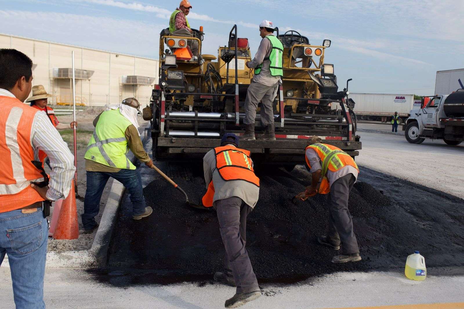 Road crew spreading hot asphalt with paving machinery during street repairs
