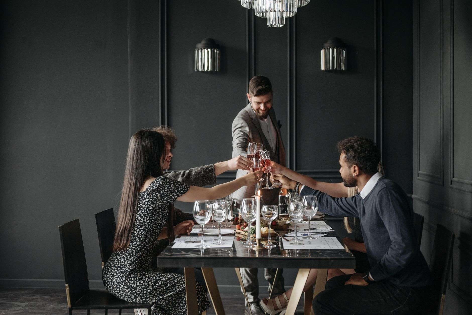 Group of adults toasting with drinks at a decorated restaurant table