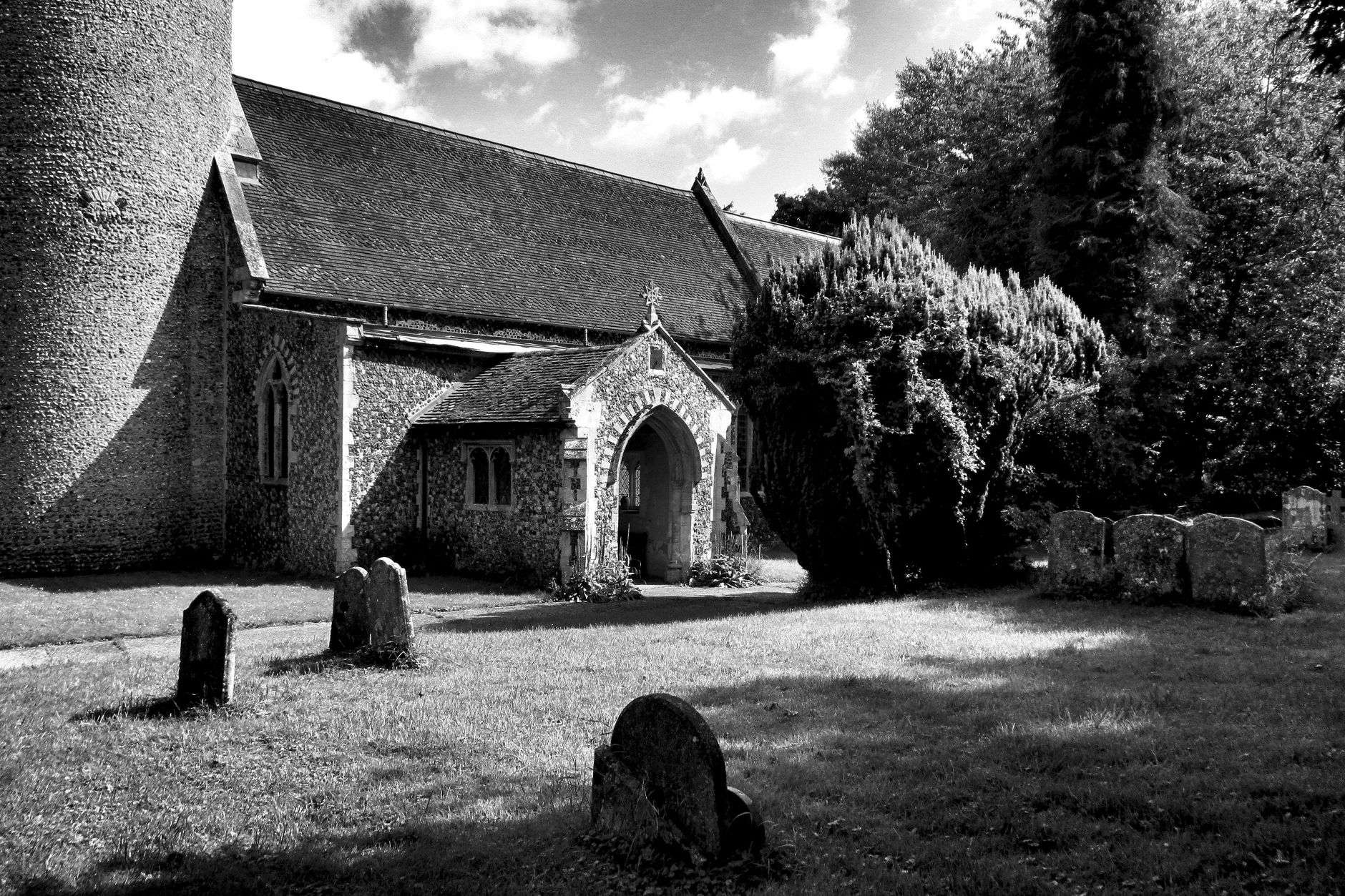 Weathered gravestones in a rural church cemetery with the church building visible in the background