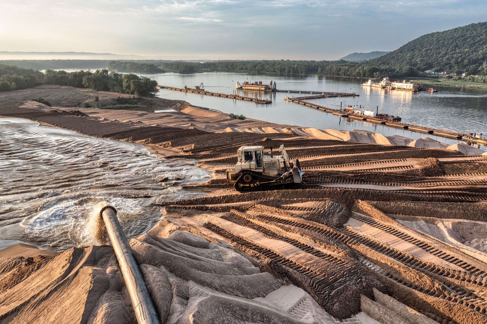A dredging barge releasing sediment material into a coastal bay near a shipping channel