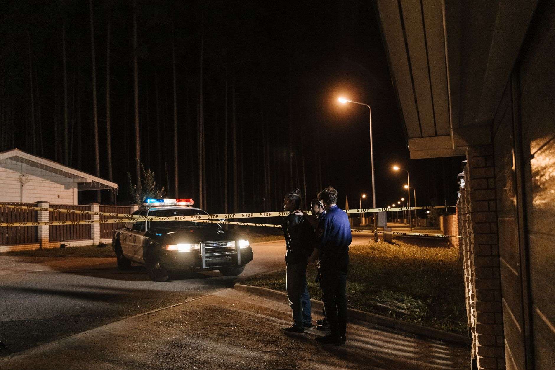 Police crime scene tape stretched across a residential street at night