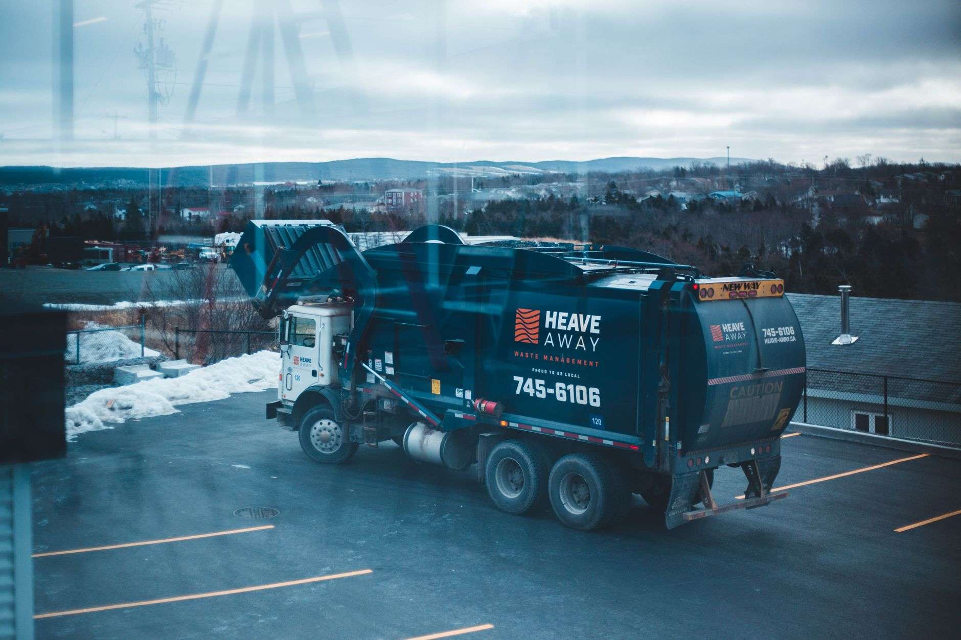 Garbage truck collecting curbside trash bins in a residential neighborhood