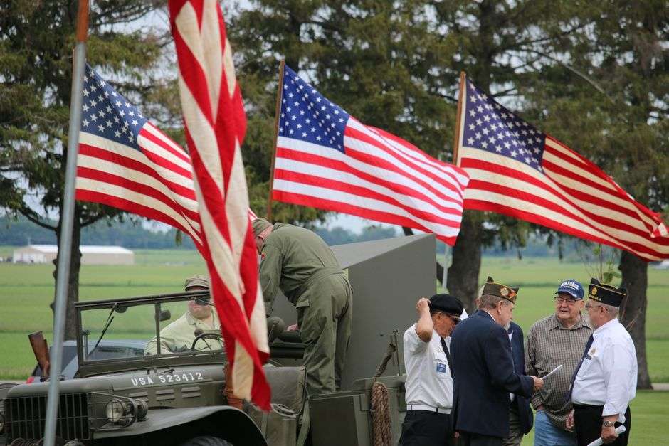 An American flag flying over rows of white headstones at a veterans cemetery