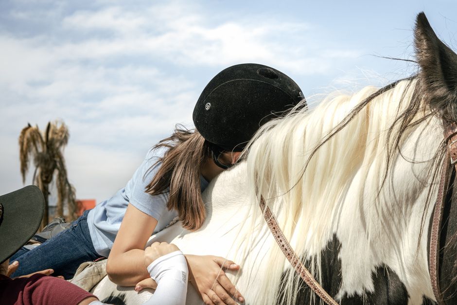 A young rider sits on a gentle horse during an equine therapy session