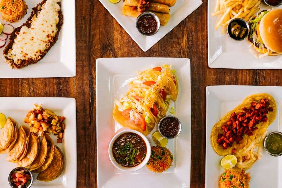 Plates of Mexican food, including tacos and enchiladas, on a restaurant table