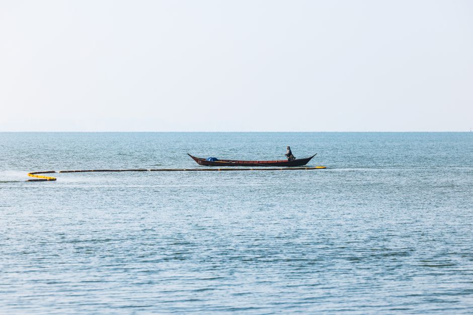 A fly angler casting across shallow coastal flats from a skiff
