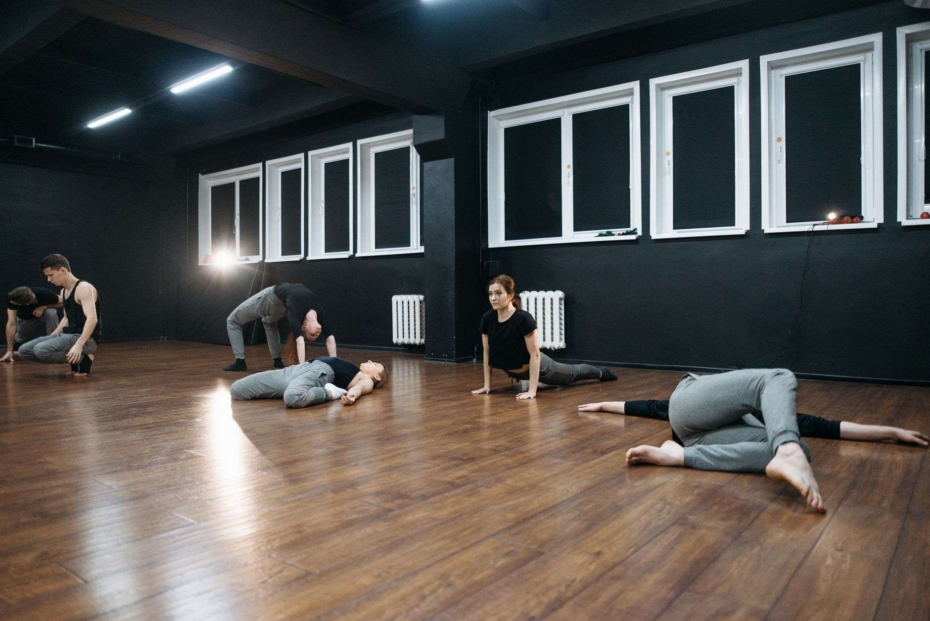 People practicing yoga on mats in a bright studio with wooden floors