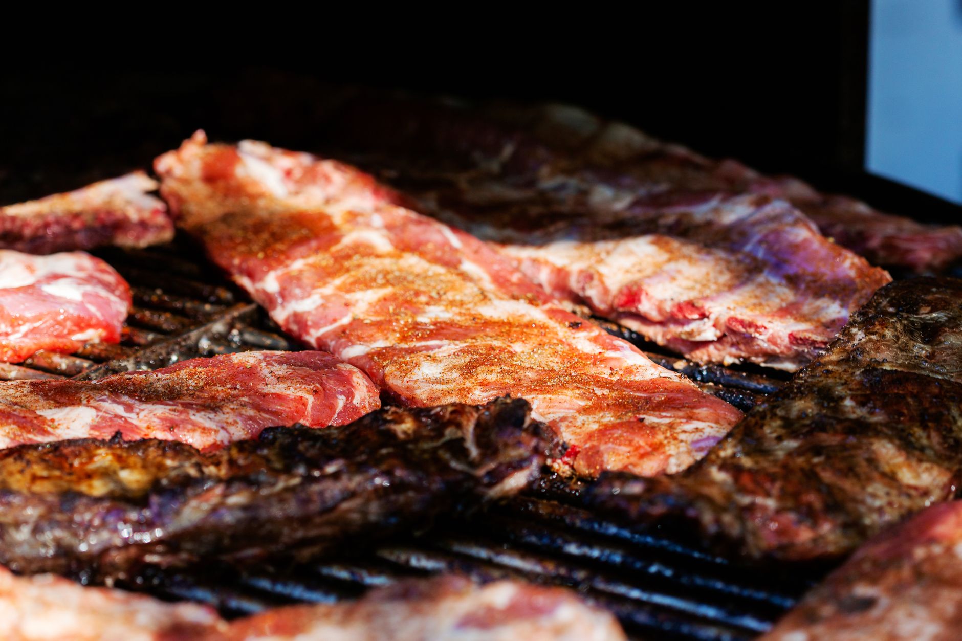 Ribs coated in dry rub seasoning cooking on a grill