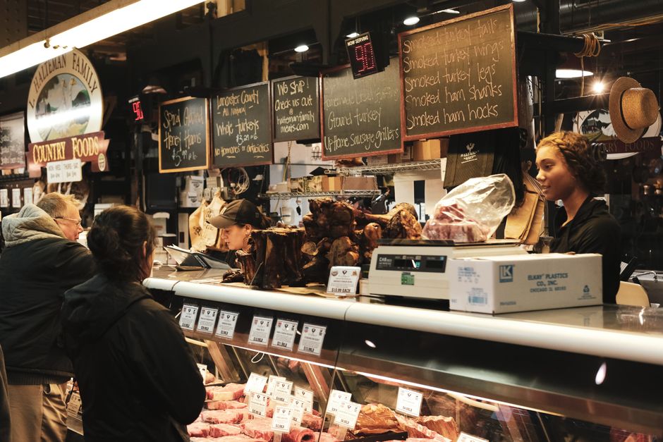 Butcher slicing fresh cuts of meat at a shop counter