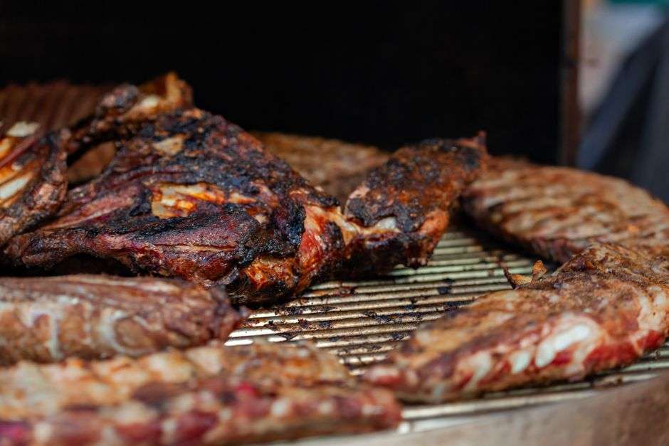 Barbecue ribs on a platter beside a backyard smoker