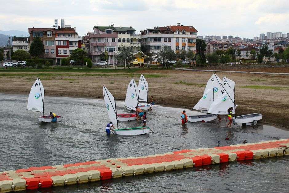 Children sailing small pram sailboats on calm bay water