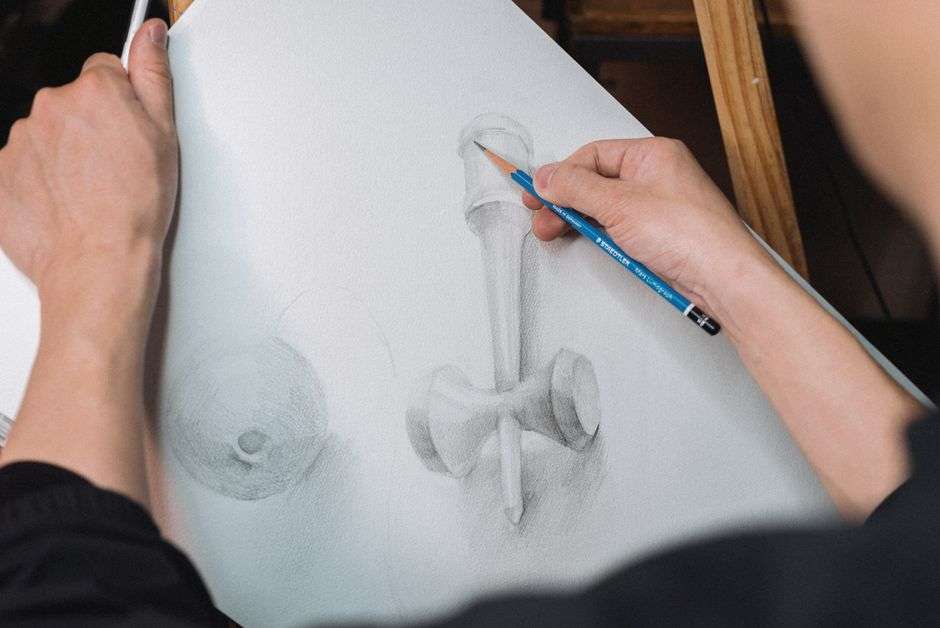 Artist working on a graphite pencil drawing at a studio desk