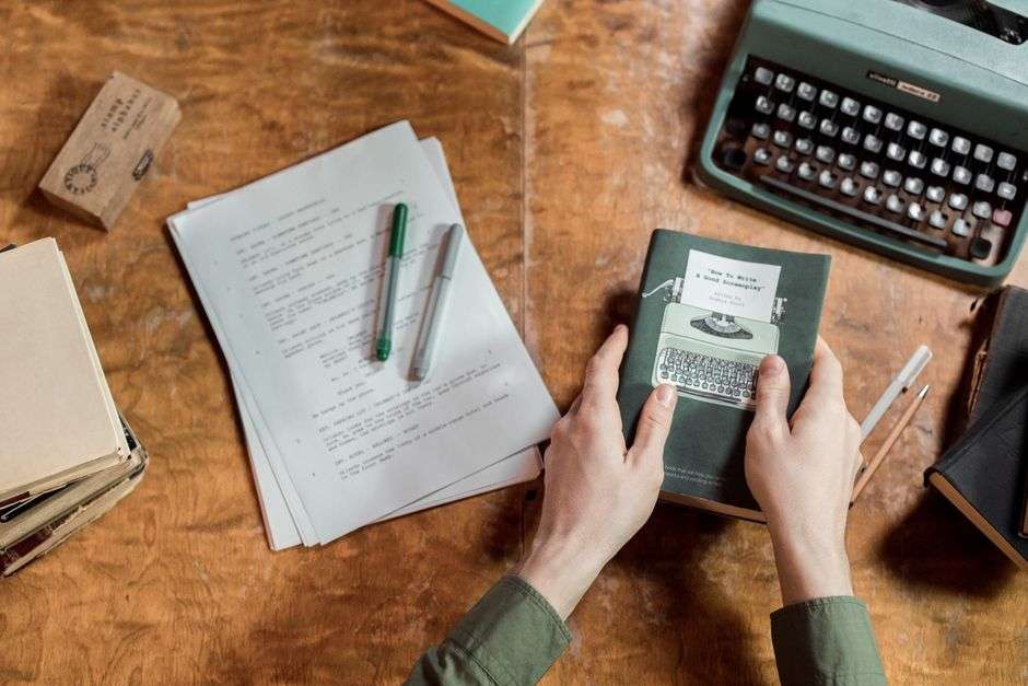 Open notebook and pen on a writing desk near a window