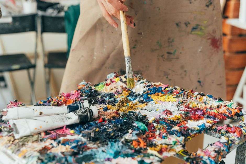 Artist painting a colorful oil canvas in a bright studio