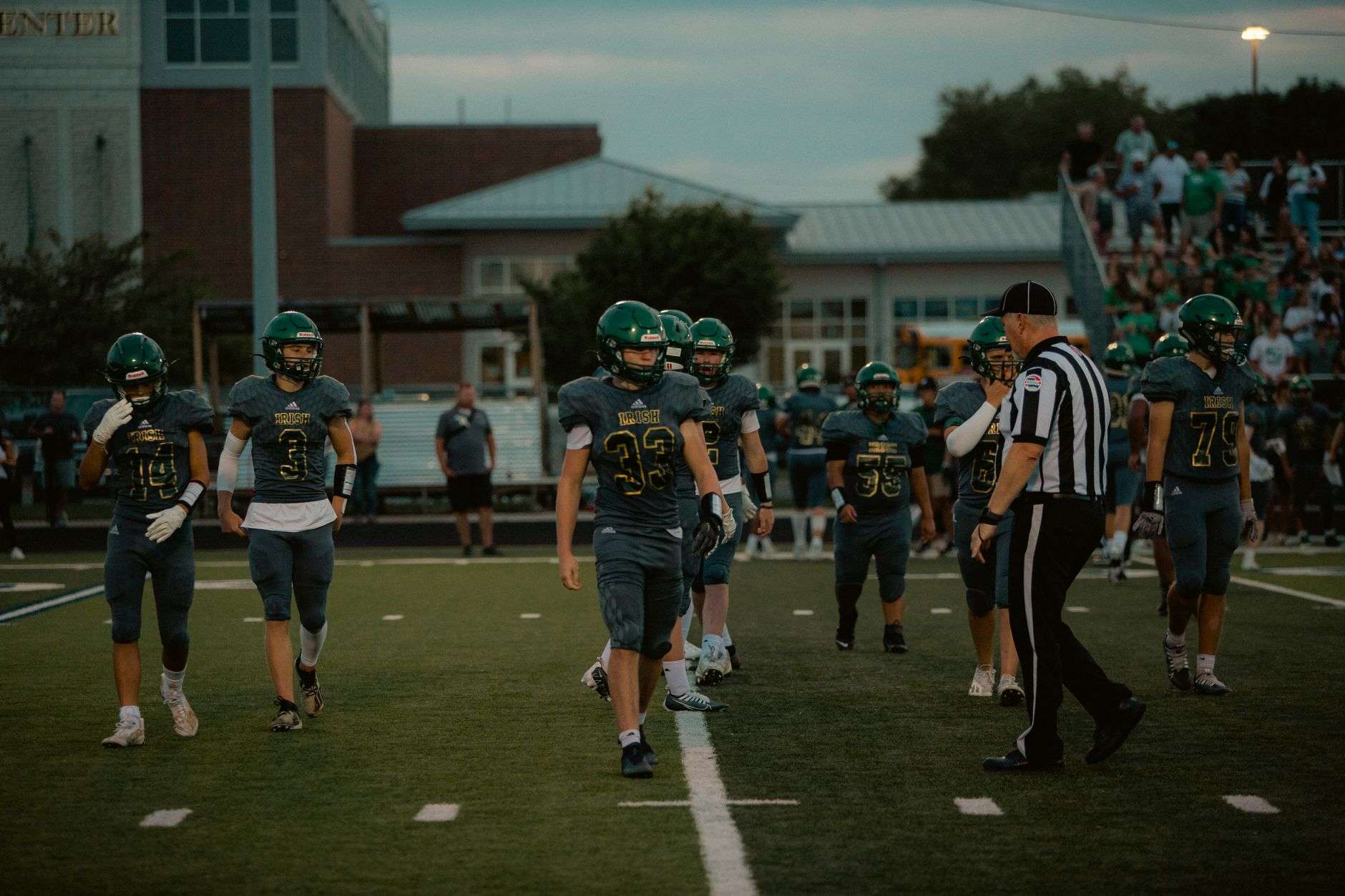 A high school football field under stadium lights, representing the end of AISA athletics